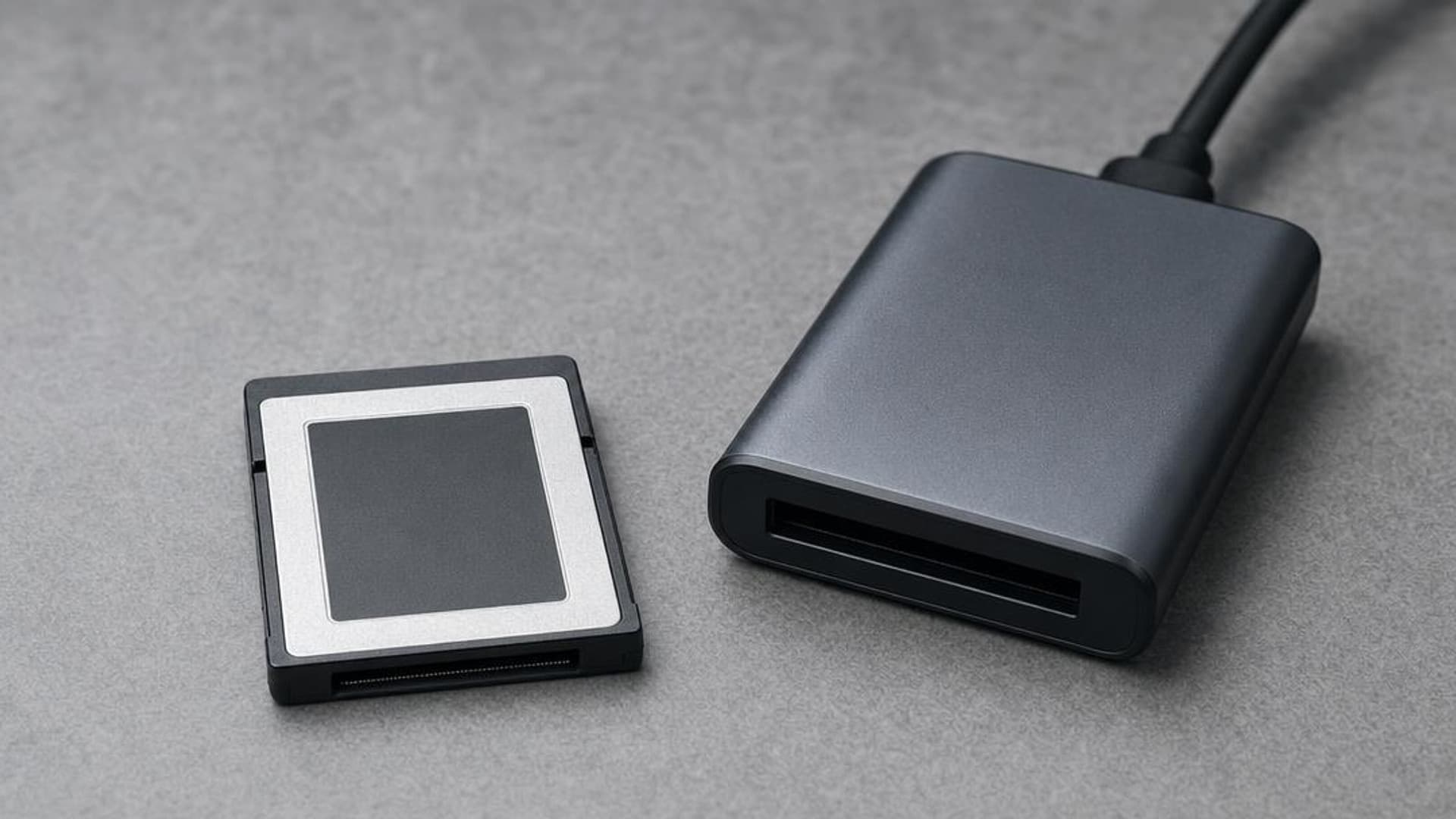 An unbranded CFexpress Type B card beside a compact card reader on a gray surface