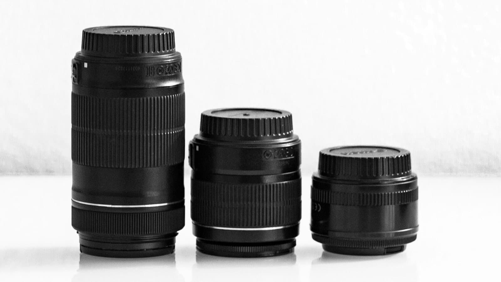Three camera lenses of different focal lengths arranged from telephoto to compact prime