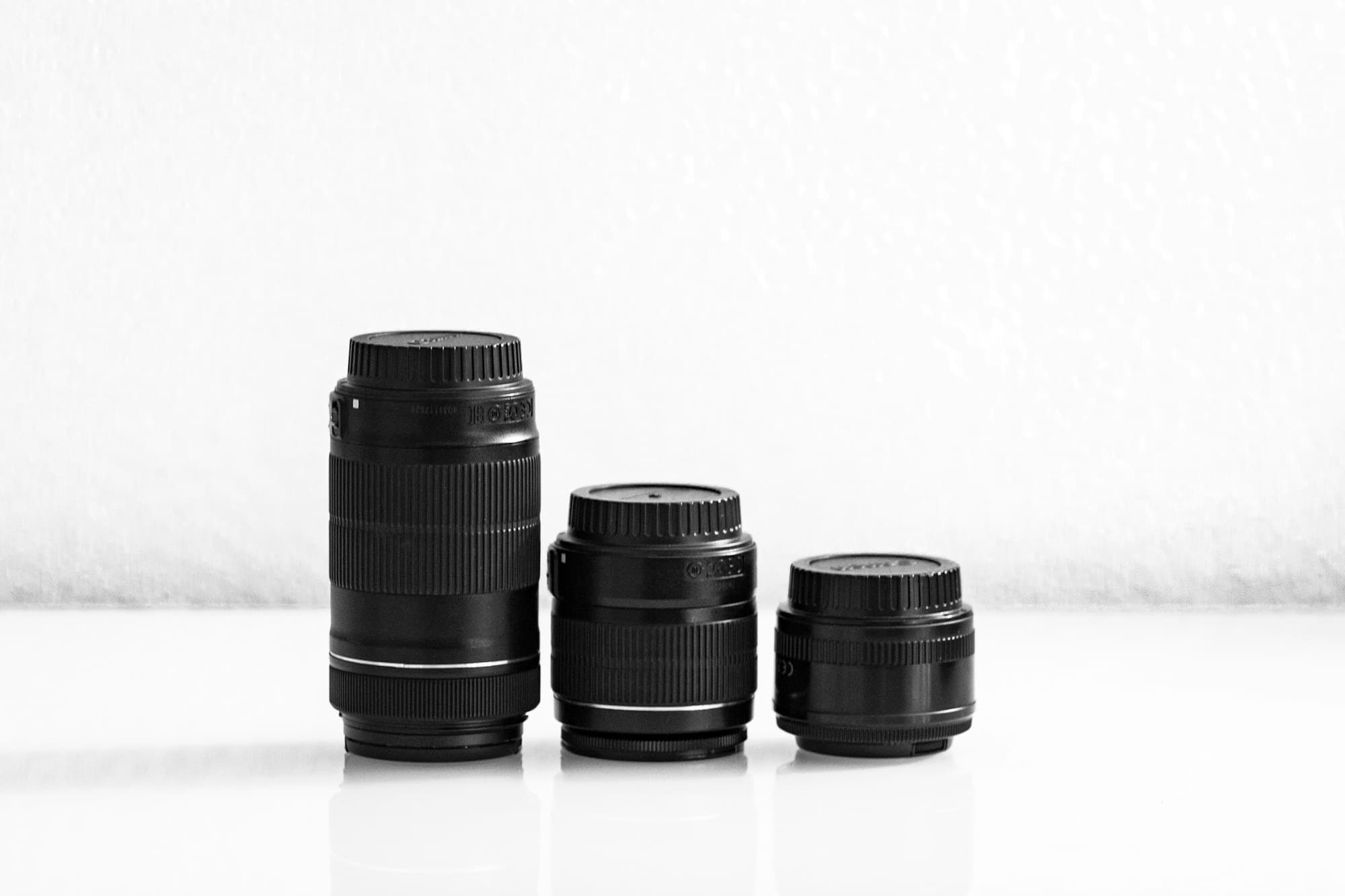 Three camera lenses of different focal lengths arranged from telephoto to compact prime