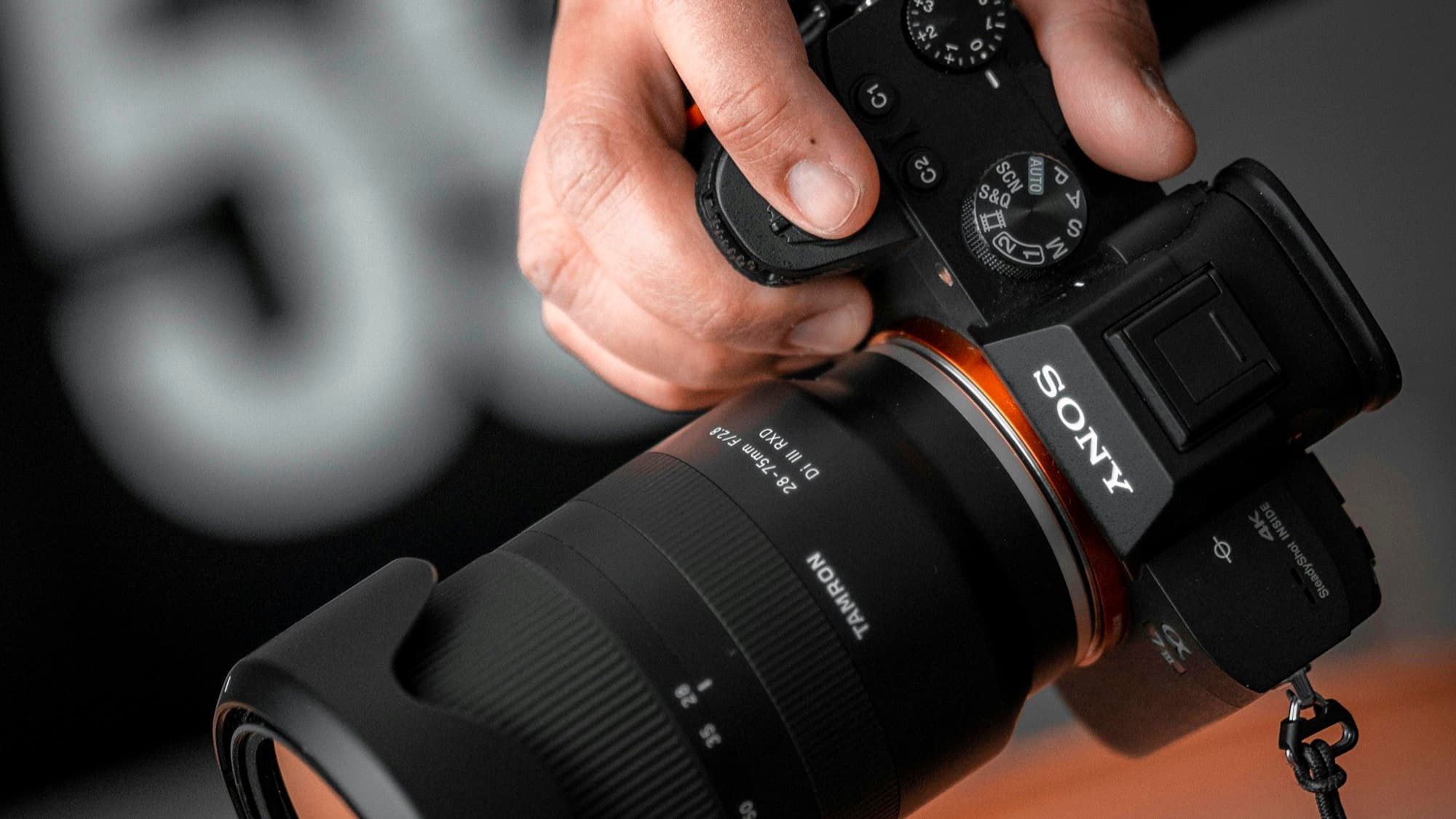 A Sony mirrorless camera held in one hand with its compact body and electronic viewfinder visible