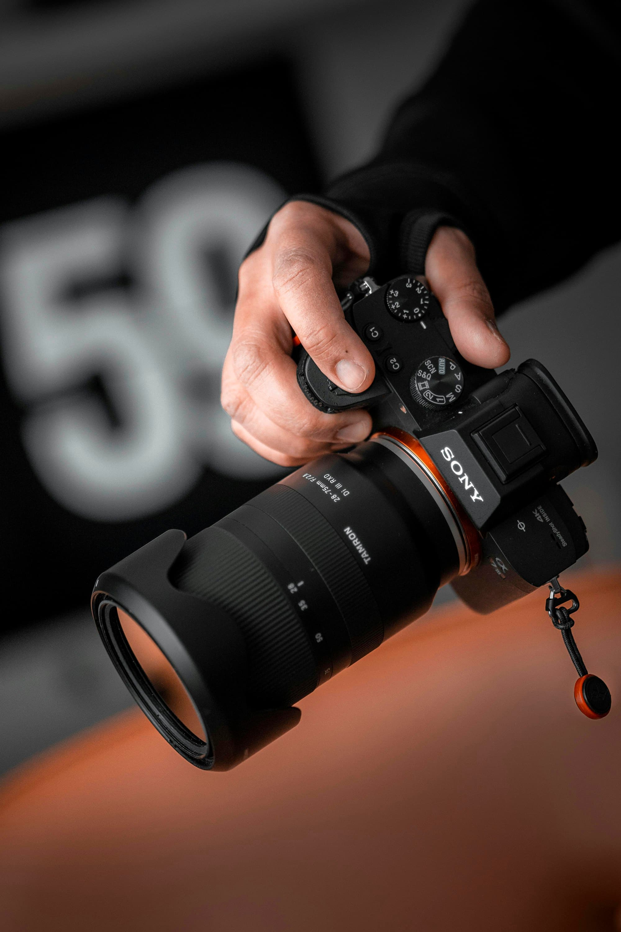 A Sony mirrorless camera held in one hand with its compact body and electronic viewfinder visible