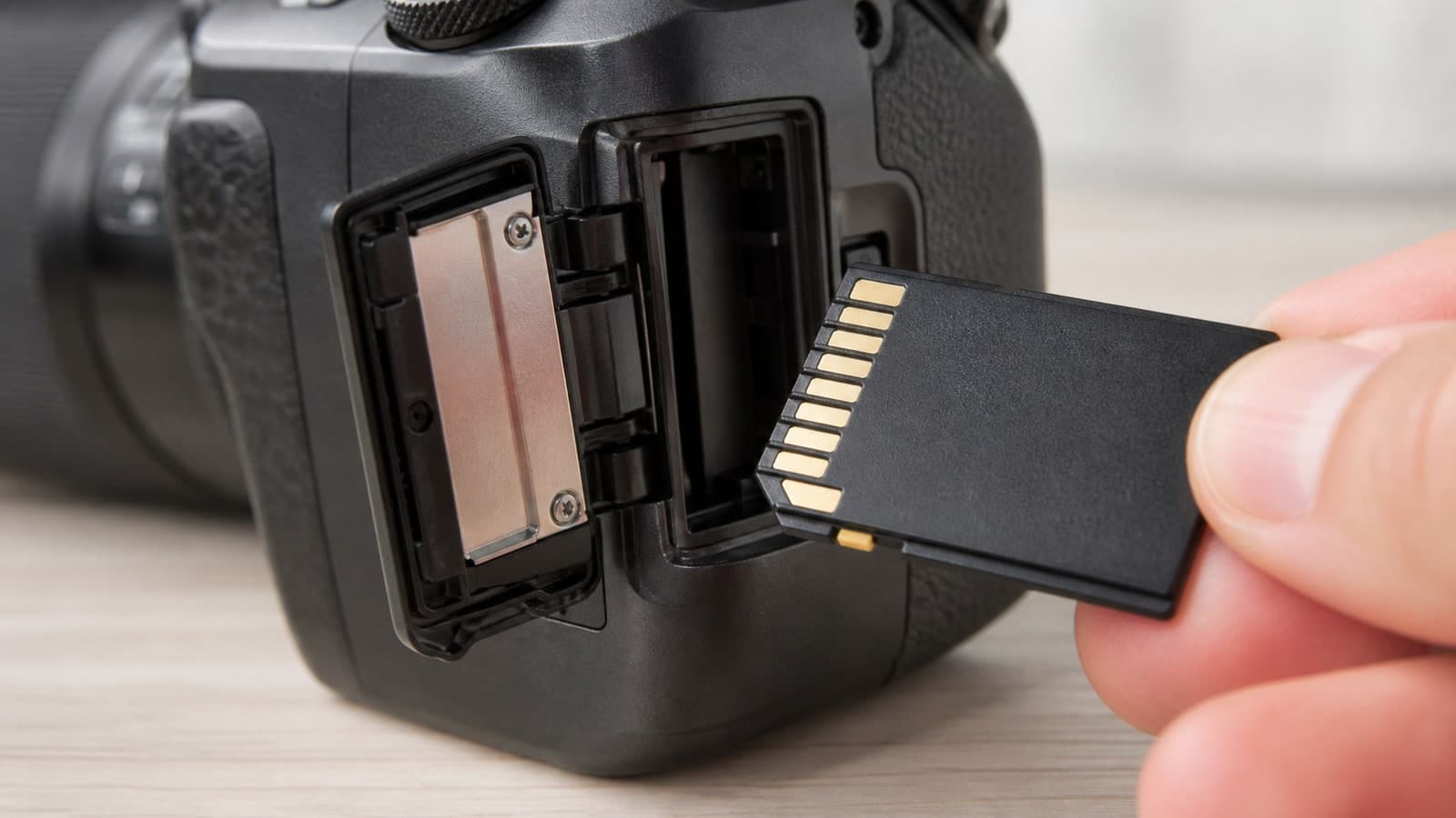 An unbranded SD memory card beside the open card slot of a mirrorless camera