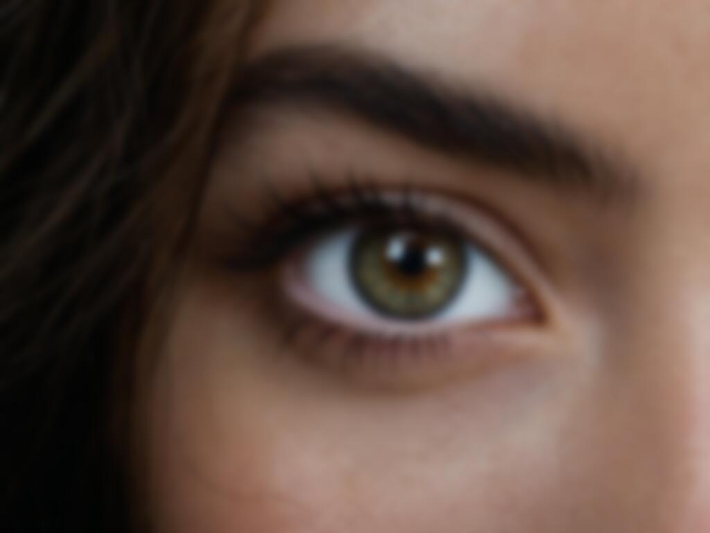 The same close-up of an eye but rendered soft and blurry, the eyelashes smeared and the iris texture lost to missed focus and camera shake, the catchlight a vague glow rather than a crisp point