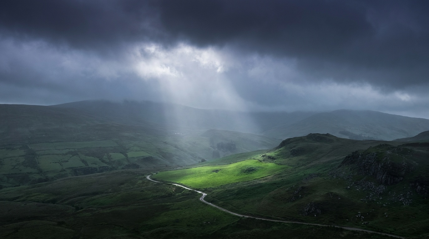 A single brilliant shaft of sunlight bursting through a wall of bruised purple storm clouds to spotlight one green hillside, the surrounding valley left in deep shadow for high-drama contrast